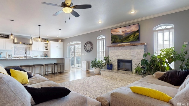 living room featuring light wood-type flooring, a ceiling fan, crown molding, recessed lighting, and baseboards