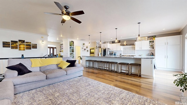 living room featuring light wood-type flooring, ceiling fan, crown molding, and recessed lighting