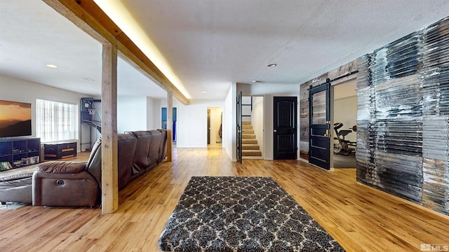 hall with a barn door, stairway, and wood finished floors