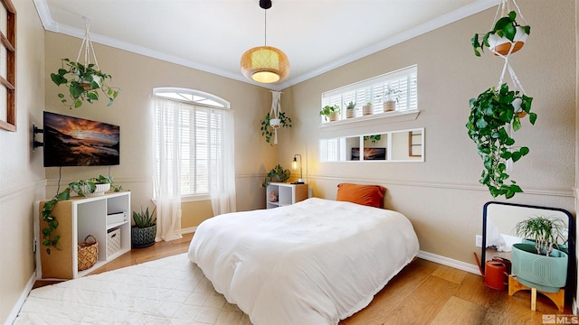 bedroom with multiple windows, crown molding, light wood-style flooring, and baseboards
