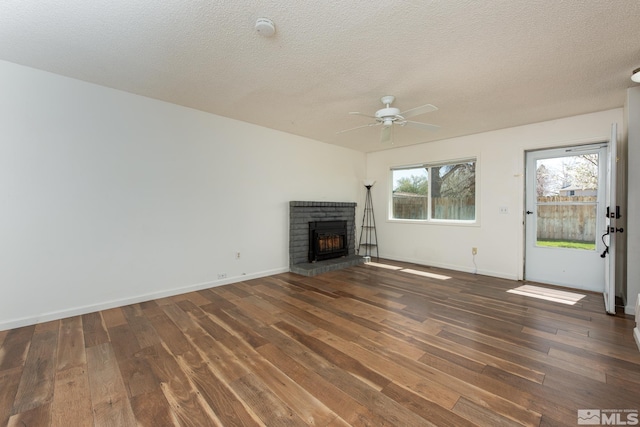 unfurnished living room featuring hardwood / wood-style flooring, a ceiling fan, a fireplace, baseboards, and a textured ceiling