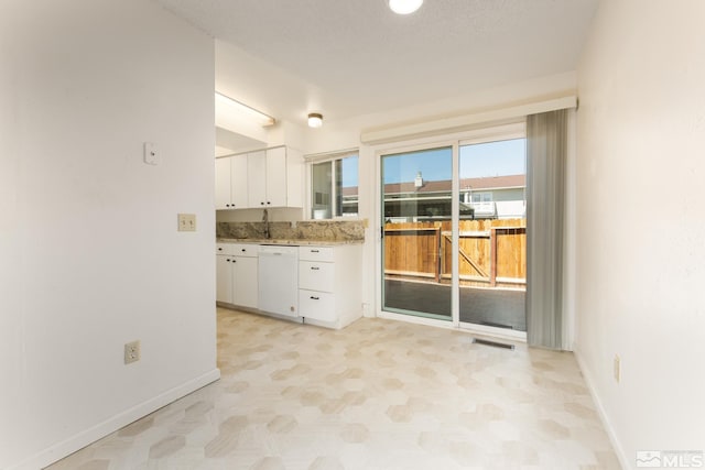 kitchen featuring white dishwasher, white cabinetry, and baseboards
