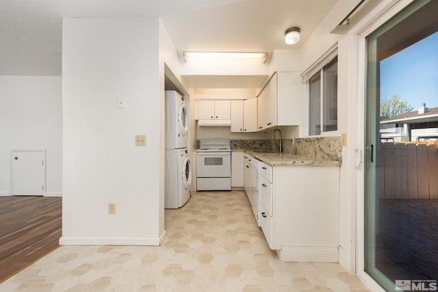 kitchen featuring white appliances, stacked washer and clothes dryer, a sink, white cabinets, and light stone counters