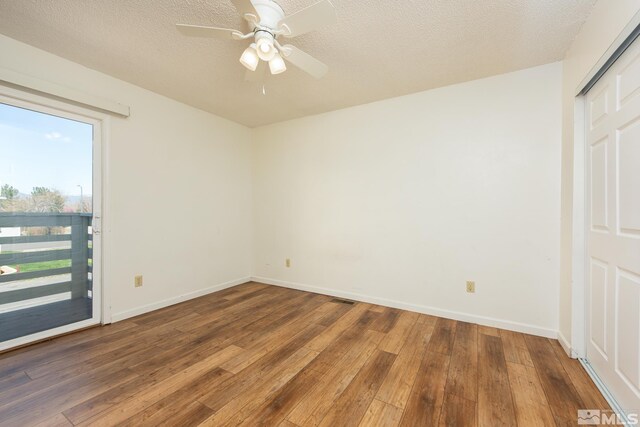 spare room featuring hardwood / wood-style flooring, baseboards, ceiling fan, and a textured ceiling