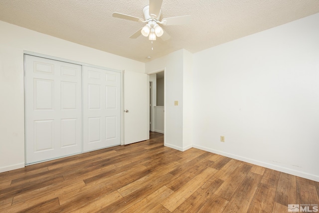 unfurnished bedroom featuring light wood-style flooring, a closet, baseboards, a ceiling fan, and a textured ceiling