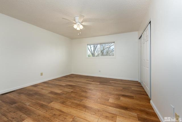 unfurnished bedroom with hardwood / wood-style floors, baseboards, a textured ceiling, a closet, and ceiling fan
