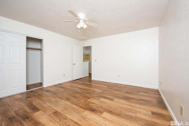 unfurnished bedroom with light wood-type flooring, baseboards, a closet, and a textured ceiling