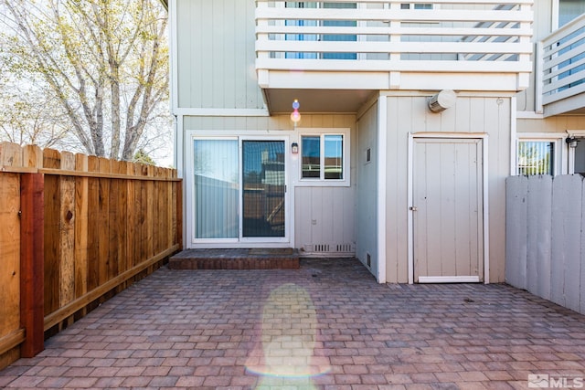 property entrance with fence and a patio