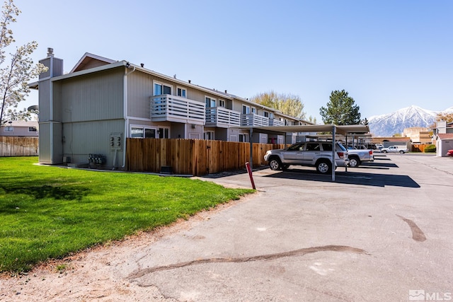 exterior space featuring covered and uncovered parking, a chimney, and a mountain view