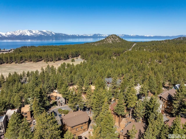 drone / aerial view of a heavily wooded area and a water and mountain view