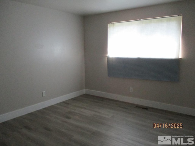 spare room featuring wood finished floors and baseboards