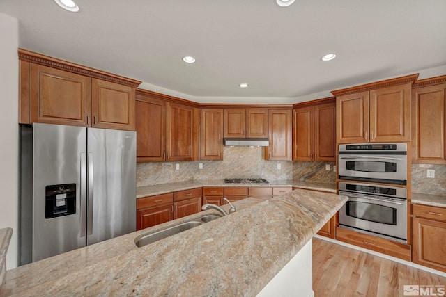 6647 Fabric Dr, Sparks, NV 89436 - kitchen with appliances with stainless steel finishes, brown cabinets, a sink, light stone countertops, and light wood finished floors