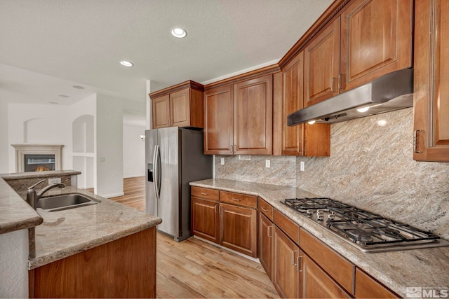6647 Fabric Dr, Sparks, NV 89436 - kitchen featuring a sink, under cabinet range hood, appliances with stainless steel finishes, light wood-type flooring, and brown cabinetry