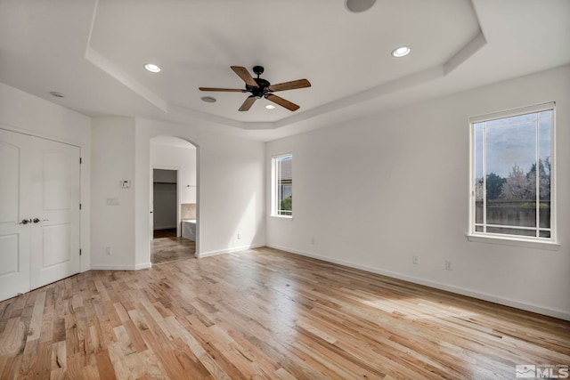 6647 Fabric Dr, Sparks, NV 89436 - unfurnished bedroom featuring a raised ceiling, arched walkways, light wood-style flooring, recessed lighting, and baseboards