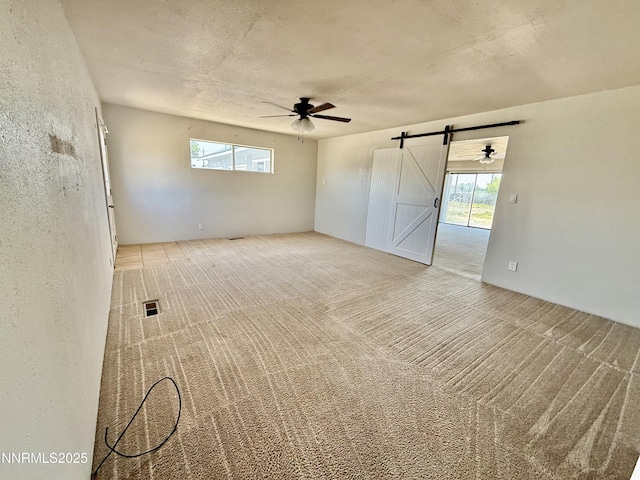 988 Gummow Dr, Fallon, NV 89406 - carpeted empty room featuring a barn door, ceiling fan, and plenty of natural light