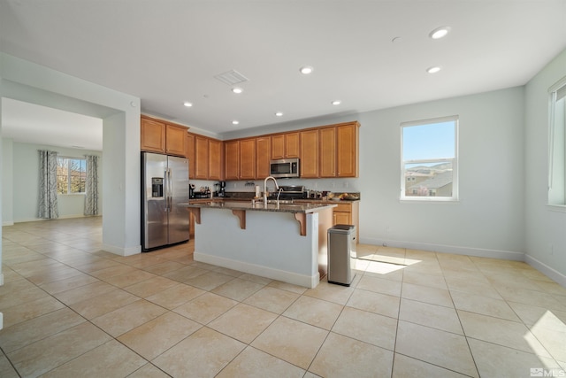 2575 Piero Ct, Sparks, NV 89434 - kitchen featuring appliances with stainless steel finishes, light tile patterned floors, dark stone countertops, a breakfast bar, and recessed lighting