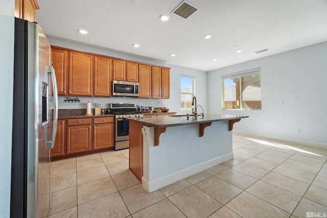 2575 Piero Ct, Sparks, NV 89434 - kitchen featuring appliances with stainless steel finishes, light tile patterned flooring, brown cabinets, a kitchen breakfast bar, and recessed lighting