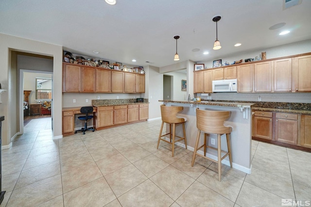 166 Oakridge Dr, Dayton, NV 89403 - kitchen with white microwave, a kitchen bar, dark stone counters, light tile patterned floors, and recessed lighting