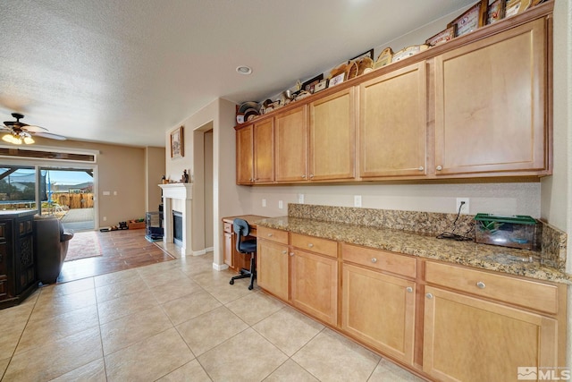 166 Oakridge Dr, Dayton, NV 89403 - kitchen featuring a ceiling fan, light tile patterned flooring, a textured ceiling, baseboards, and light stone counters