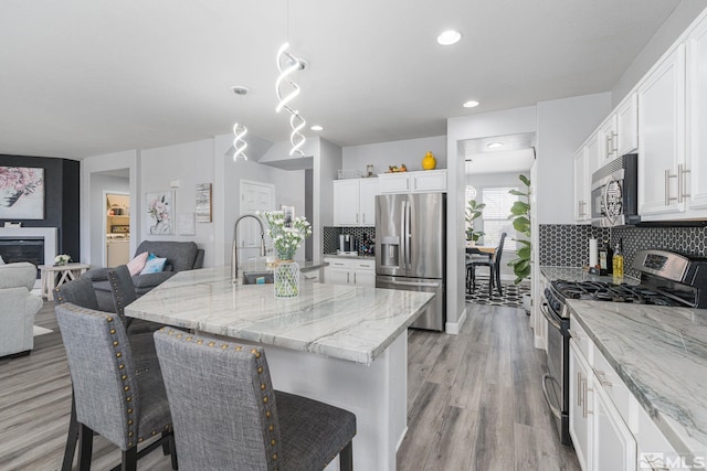 450 Ruffian Ct, Reno, NV 89521 - kitchen with appliances with stainless steel finishes, light wood finished floors, backsplash, open floor plan, and light stone countertops