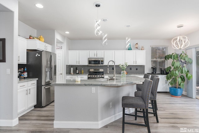 450 Ruffian Ct, Reno, NV 89521 - kitchen with appliances with stainless steel finishes, white cabinets, backsplash, light wood finished floors, and light stone counters