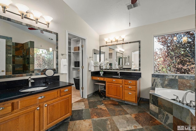 2116 Frisco Way, Sparks, NV 89434 - full bathroom featuring lofted ceiling, stone tile floors, healthy amount of natural light, a garden tub, and two vanities