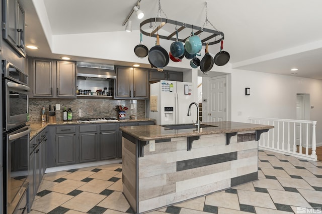 960 Country Ridge Dr, Sparks, NV 89434 - kitchen with appliances with stainless steel finishes, a sink, lofted ceiling, decorative backsplash, and dark stone countertops