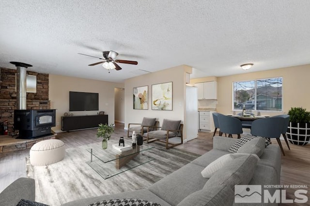 68 Zircon Dr, Reno, NV 89521 - living area featuring a textured ceiling, a wood stove, a ceiling fan, and wood finished floors