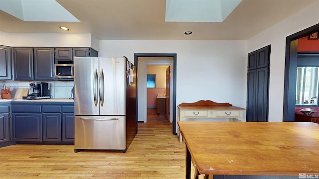 kitchen with freestanding refrigerator, light wood finished floors, recessed lighting, a skylight, and decorative backsplash
