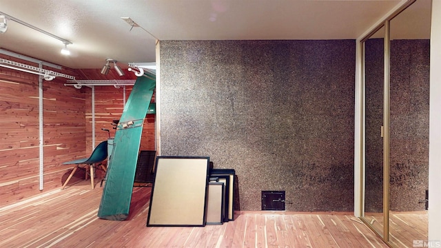 basement with hardwood / wood-style floors and track lighting