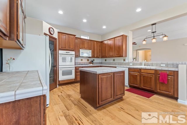 9900 Wilbur May Pkwy Unit 2704, Reno, NV 89521 - kitchen with white appliances, a sink, light wood-type flooring, arched walkways, and brown cabinets
