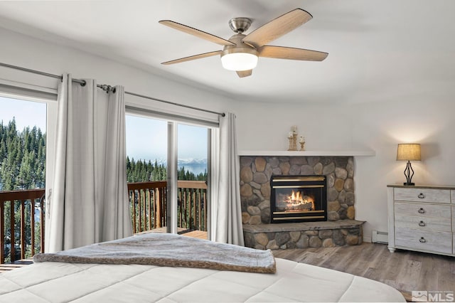 400 Fairview Blvd Unit 86, Incline Village, NV 89451 - bedroom with access to exterior, wood finished floors, a stone fireplace, a baseboard heating unit, and multiple windows