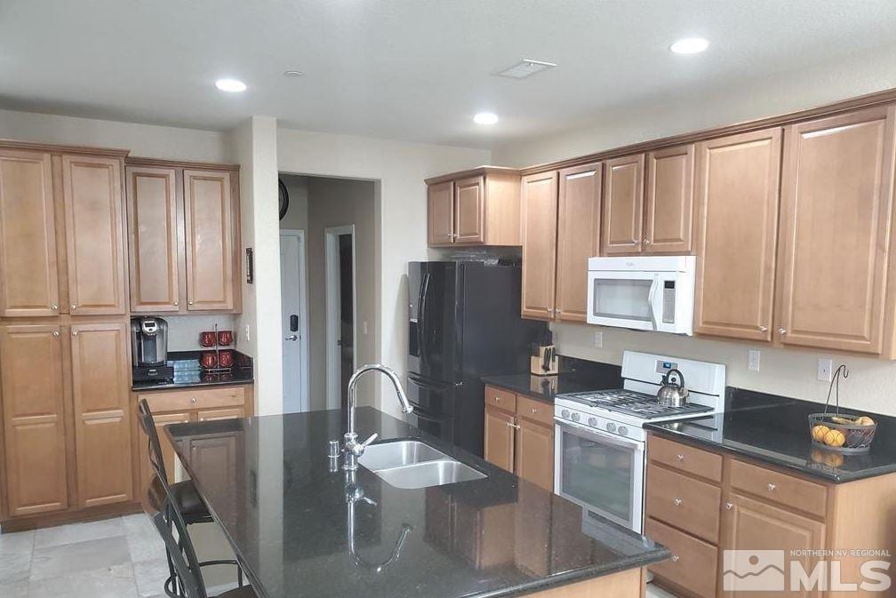 2726 Alessandro Dr, Sparks, NV 89434 - kitchen with white appliances, a sink, an island with sink, dark stone counters, and recessed lighting