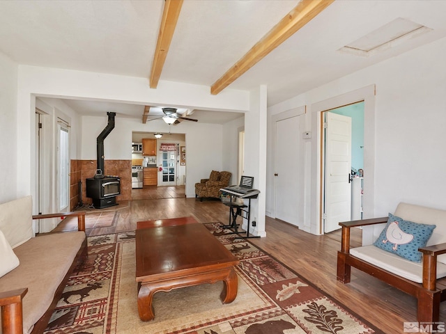 325 Stock Ln, Fernley, NV 89408 - living area featuring a wood stove, wood finished floors, plenty of natural light, beam ceiling, and ceiling fan