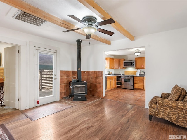 325 Stock Ln, Fernley, NV 89408 - living room with a wood stove, beamed ceiling, light wood-style flooring, ceiling fan, and tile walls