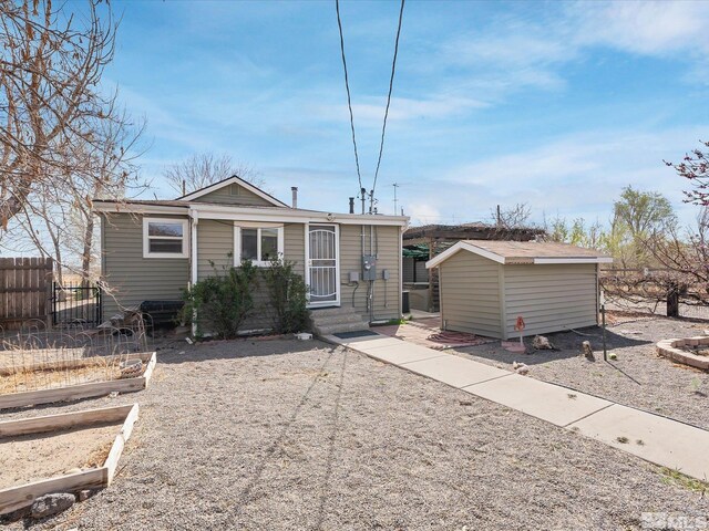 325 Stock Ln, Fernley, NV 89408 - view of front of house featuring a vegetable garden, a storage unit, an outbuilding, and fence