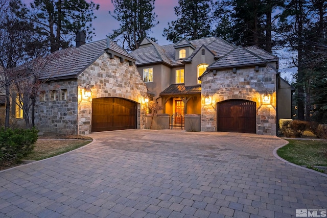 6554 Champetre, Reno, NV 89511 - french country style house featuring stone siding, a chimney, a garage, decorative driveway, and stucco siding