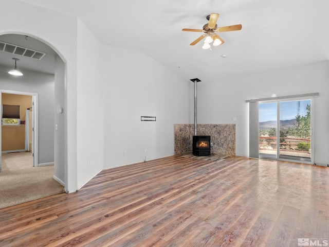 1974 Spring Rd, Fernley, NV 89408 - unfurnished living room with wood finished floors, arched walkways, vaulted ceiling, a ceiling fan, and a wood stove