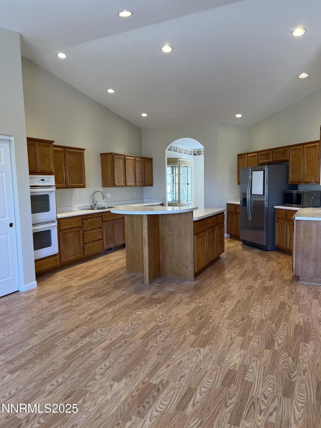 1974 Spring Rd, Fernley, NV 89408 - kitchen featuring appliances with stainless steel finishes, light wood-style floors, lofted ceiling, a center island, and light countertops