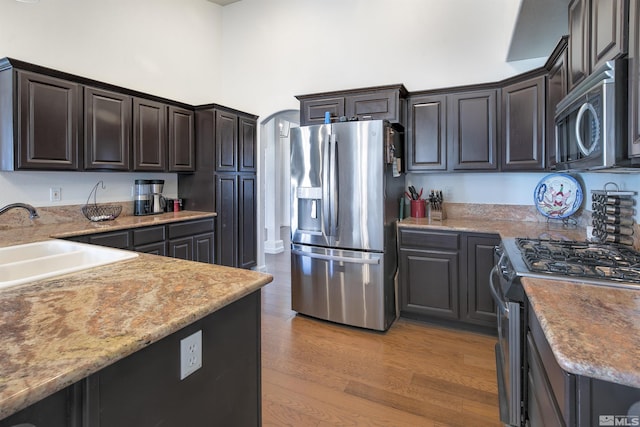 1675 Skyridge Dr, Fallon, NV 89406 - kitchen featuring appliances with stainless steel finishes, a sink, light wood-style flooring, a towering ceiling, and light stone countertops