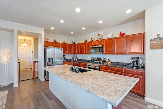 kitchen with appliances with stainless steel finishes, a sink, recessed lighting, light wood-style flooring, and baseboards