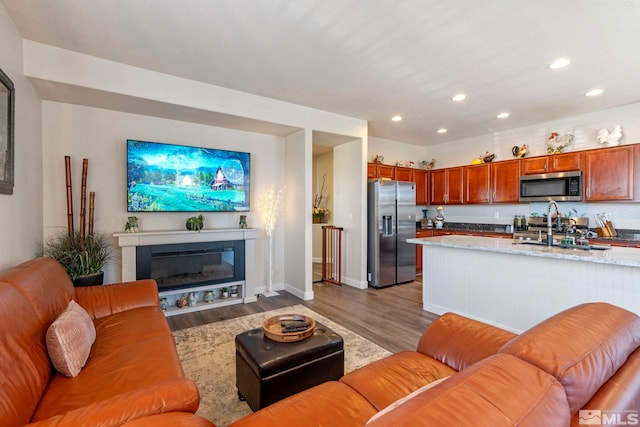 living room with recessed lighting, wood finished floors, a glass covered fireplace, and baseboards