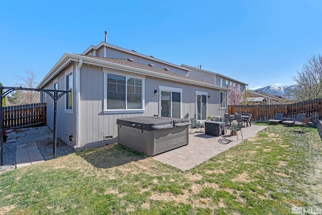 rear view of property featuring a hot tub and a patio area