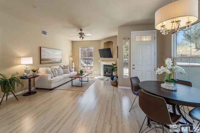 17000 Wedge Pkwy Unit 111, Reno, NV 89511 - living room featuring light wood-type flooring, baseboards, a ceiling fan, a glass covered fireplace, and a chandelier