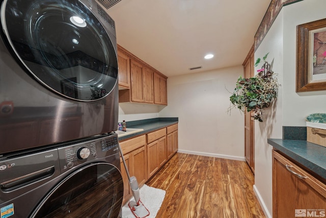 951 Riverview Dr, Gardnerville, NV 89460 - laundry area featuring stacked washing machine and dryer, cabinet space, light wood finished floors, baseboards, and recessed lighting