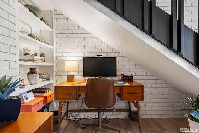 home office featuring wood finished floors, vaulted ceiling, and brick wall