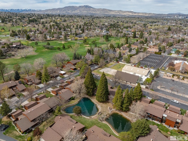view of property location featuring a mountainous background, a golf club, and nearby suburban area