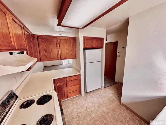4985 W 7th St Unit 11, Reno, NV 89503 - kitchen featuring white appliances, brown cabinets, light countertops, under cabinet range hood, and light tile patterned floors