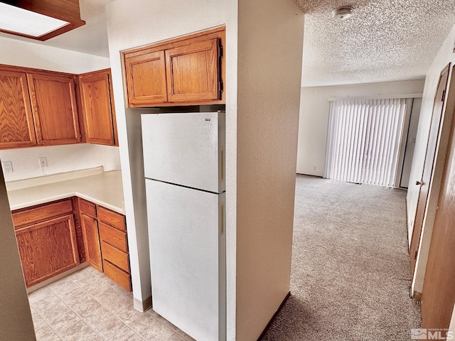 4985 W 7th St Unit 11, Reno, NV 89503 - kitchen featuring freestanding refrigerator, brown cabinets, light countertops, light colored carpet, and a textured ceiling