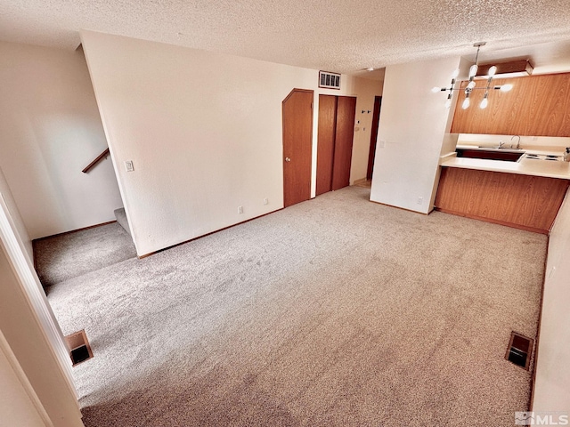 4985 W 7th St Unit 11, Reno, NV 89503 - unfurnished living room featuring light carpet, a textured ceiling, a chandelier, stairway, and a sink